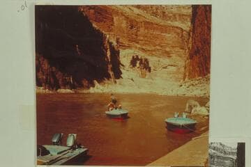 Belknap, in the "Cactus," pulls away from the beach just below Vaseys Paradise, Marble Canyon. Jorgen Visbak is standing on the stern, and Willie Taylor is sitting on Belknap's right