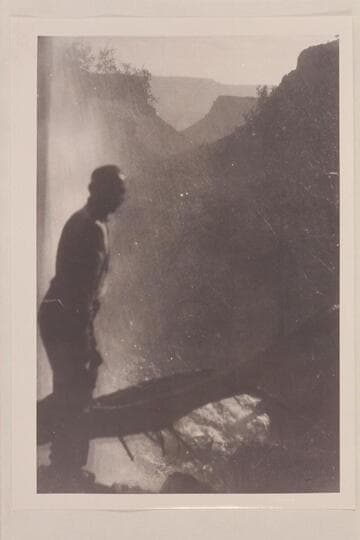 Ellsworth Kolb standing under the falls at head of Clear Creek. Kolb and Israel Hoyt Chamberlain visited the falls in 1908