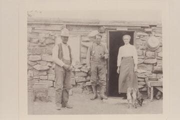 Stone cabin at the foot of the Vermillion Cliffs.  Lee started construction of a stone cabin and this may have been completed later as shown.  The man at left appears to be J. R. Bevard