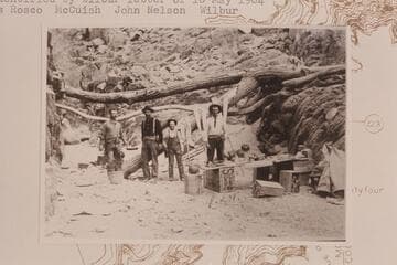 Prospecting party at breakfast probably at Diamond Creek. Identified by Wilbur letter of 1904, May 10 as Rosco; McCuish; John Nelson; Wilbur