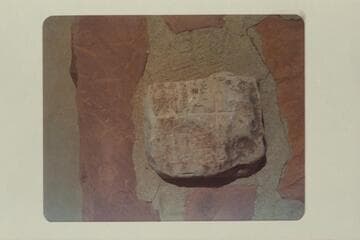 The stone with the cross on it which marked the north end of the Powell baseline in Kanab. It was formerly in the street but is now on top of the monument at the corner of the streets
