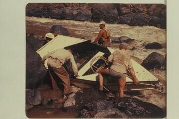 Portage of "Mexican Hat III" at Vulcan Rapid. Duane Bishop is at the stern. Willard Wright is on the far side. Frank Wright and Bill Thompson on the near side do not appear to need the safety of a life preserver
