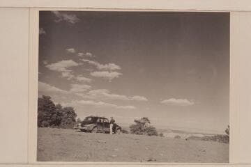 Chet Bundy stands by our car near the top of Mt. Logan. The Grand Canyon appears in the distance