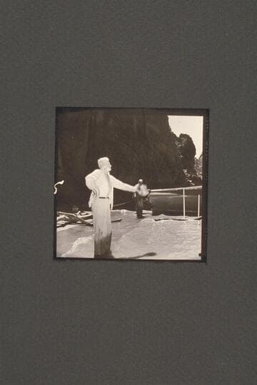 Joe Desloge carries on various activities during the repair of the "Cactus" below Tuna Creek Rapid. Here he waves directions while Rod Sanderson watches