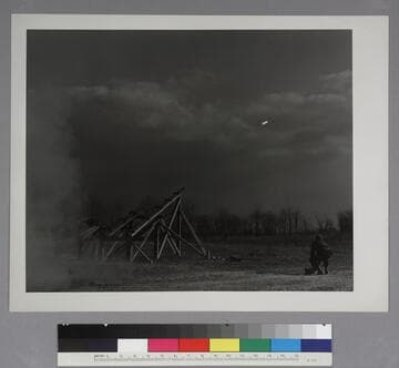 A rocket launched from wooden scaffolding over a tree-lines field