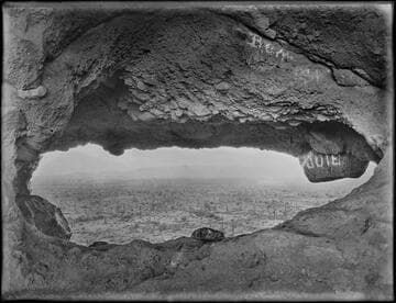 Cave opening in cliff with graffiti