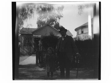 Man standing with a girl with a house behind them