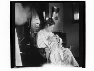 Woman holding baby, sitting in chair