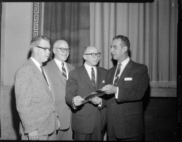 Four men processing a document