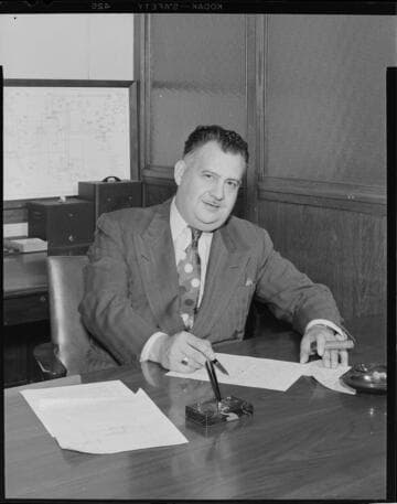 Ray Fisher seated at his desk with cigar in-hand