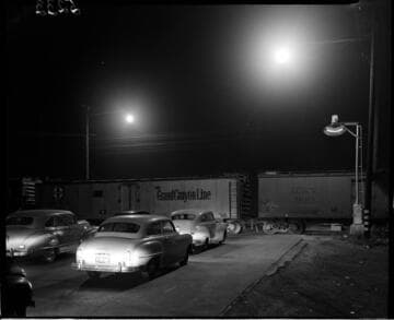 Cars stopped at a railroad crossing while train passes