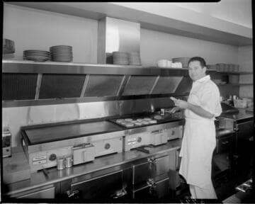 Man cooking burgers on grill at Minute Man Snacks