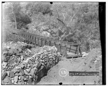 Station 64 at the end of a flume of Kaweah #2 Hydro Plant showing a rock wall and trees