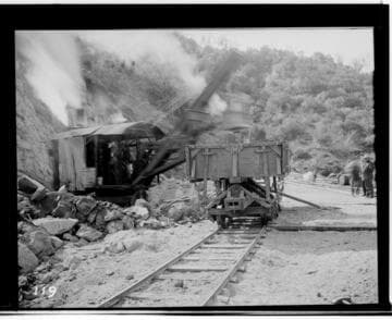 View of the steam shovels working on the reservoir of Kaweah #3 Hydro Plant. showing railway tracks. rocks. and mountains in the background. ca. 1913.  (This photo is out of focus. but otherwise. very similar to N-