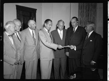 Seven executives posing for check presentation