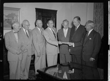 Seven executives posing for check presentation