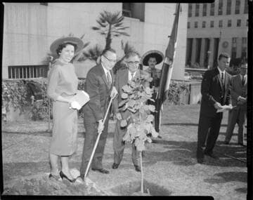 Ceremonial tree planting with people in business attire on lawn