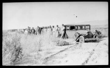 Several cars and men in the desert