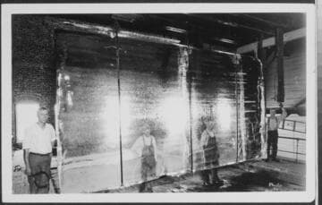 Men working with a huge suspended sheet of ice in the Imperial Ice House