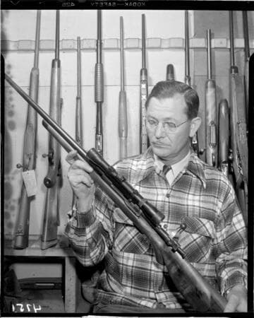 Man holding bolt action hunting rifle with scope