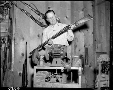 Man standing by buffer holding double barrel shotgun