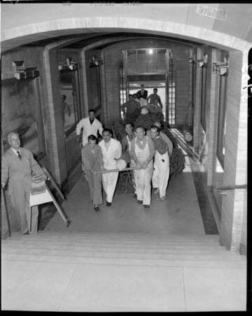 Men bringing Christmas tree up into Edison General Office lobby from street