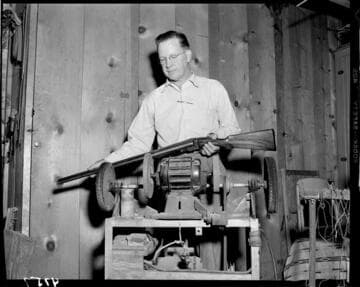 Man standing by buffer holding double barrel shotgun