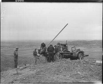 Men using power auger rig on truck to dig hole for pole placement