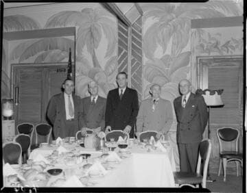 Five men standing at the head of a banquet table