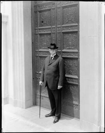 Portrait of Henry E. Huntington in front of bronze doors, approximately 1922