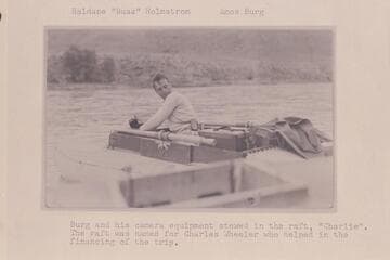 Haldane "Buzz" Holmstrom; Amos Burg. Burg and his camera equipment stowed in the raft "Charlie." The raft was named for Charles Wheeler, who helped in the financing of the trip