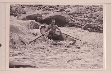Norm Nevills at 13 Foot Rapid, San Juan River.  The boat is one of Ansel Hall's folding spruce skiffs and the river flow is less than 400 cfs