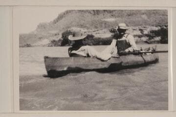 George C. Fraser sitting in the stern of one of Dave Rust's boats which is being rowed by Bert Loper; Glen Canyon