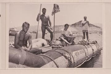 The crew of the Bolte-Eaton party with the pontoon "Driftwood" at the boat landing at Boulder City where they arrived 1954, July 11.Bolte is at left; LeRoy Byers holds the oar; Carl Gage and Earl Eaton are at right