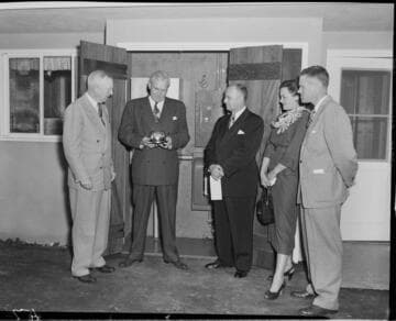 Three Edison men presenting "one millionth" meter to owners in back yard of home