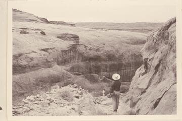 Looking down the old Stanton Dredge road. Nancy Gilmer in foreground is standing on bedrock. Harry Aleson stands on another section of the road in the background. All the roadbed has washed away down through the middle section