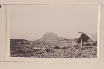 Looking northeast up San Juan Canyon from point between mouths of Clay Gulch and Copper Canyon. Camp is on gravel terrace. Mesa is capped by Navajo, Todilto, and Wingate formations. Irregular hills are in areas of Chinle formation