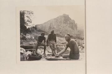 Moulty Fulmer toasting bread at Nancoweap Camp. Others figures are Nevills and Masland