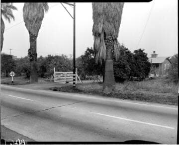 Gate to a small wooden farm house as seen from across a road