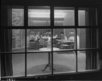 View through window of husband and wife reading in their living room