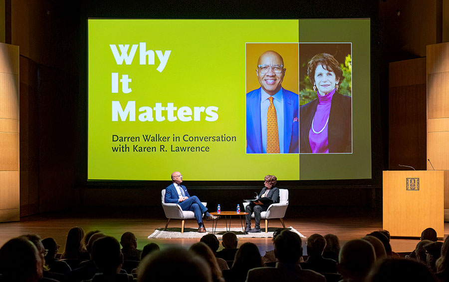 An audience watches two people have a conversation on a stage, where a large graphic says, “Why It Matters.”