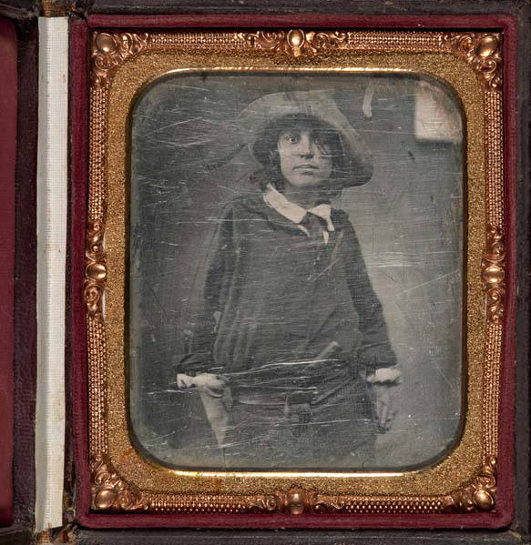 A golden-tone frame with red velvet accents surrounds a portrait of a man standing slouched in oversized clothes.