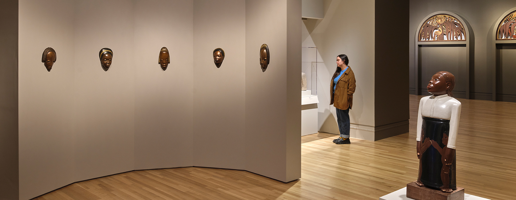 A person stands in a gallery filled with sculptures.
