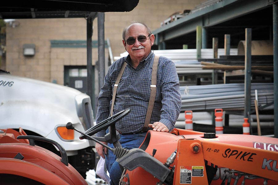 A person stands next to an orange tractor nicknamed Spike.