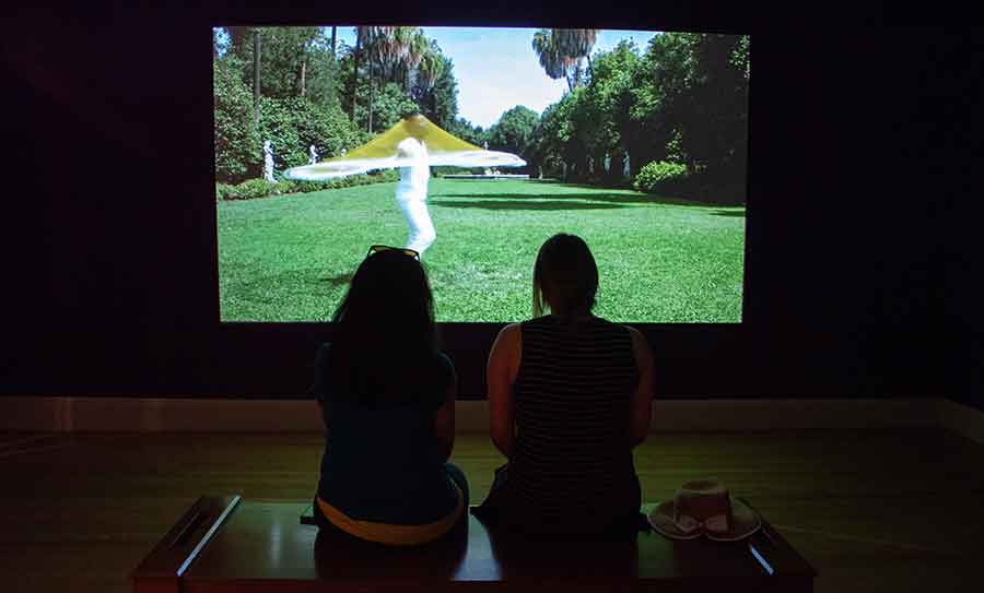 Visitors sitting in front of Carolina Caycedo video