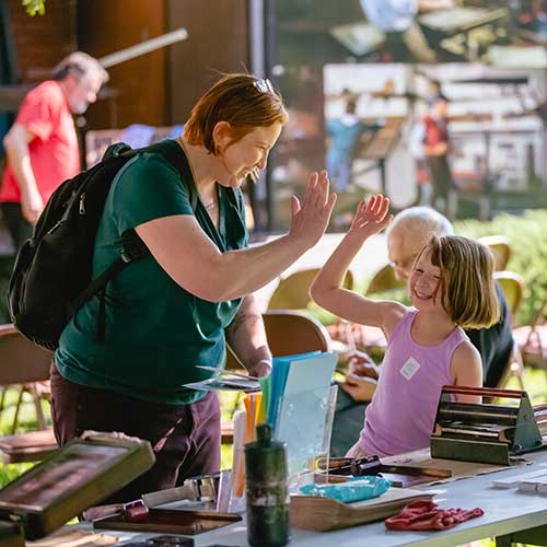 Mom and daughter high-fiving at activity station