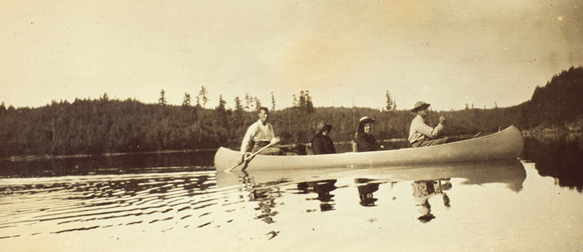 The label for this image in one of the Turners’ photograph albums of their 1908 canoe trip reads: “Kahnipiminanikok / Dow and the Turners en route.” “Kahnipiminanikok” is the Ojibwe name of Kawnipi Lake in Ontario, Canada. Seated in the bow seat is historian Frederick Jackson Turner (far right); behind him sits his wife, Caroline Mae Turner (second from right) and their daughter, Dorothy K. Turner (third from right). Jesse Dow (far left), one of the trip guides, sits in the stern seat, steering the canoe. Unidentified photographer. The Huntington Library, Art Collections, and Botanical Gardens.