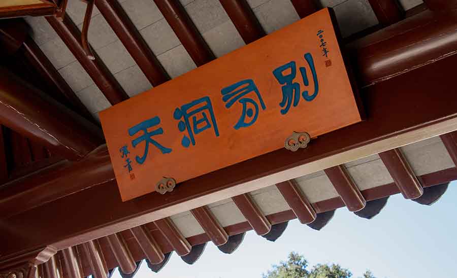 A wooden placard that reads “Another World Lies Beyond.”