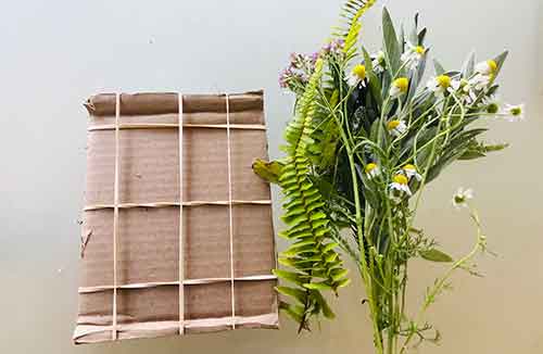 Cardboard loom with bundle of herbs