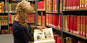 A scholar inspecting a book in the library stacks